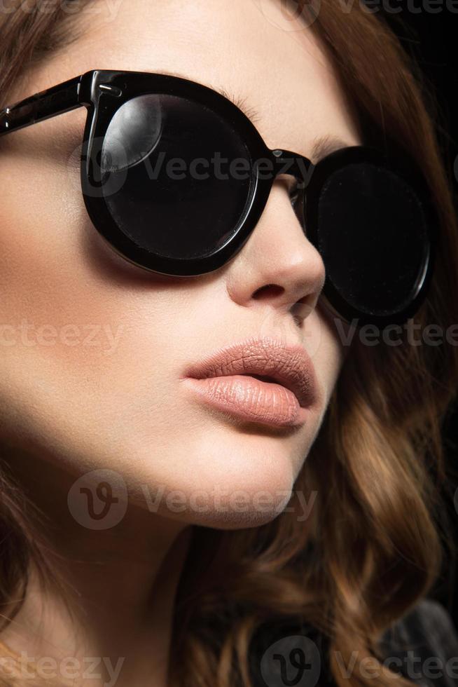 garota bonita de óculos escuros, com cachos e maquiagem de noite. foto