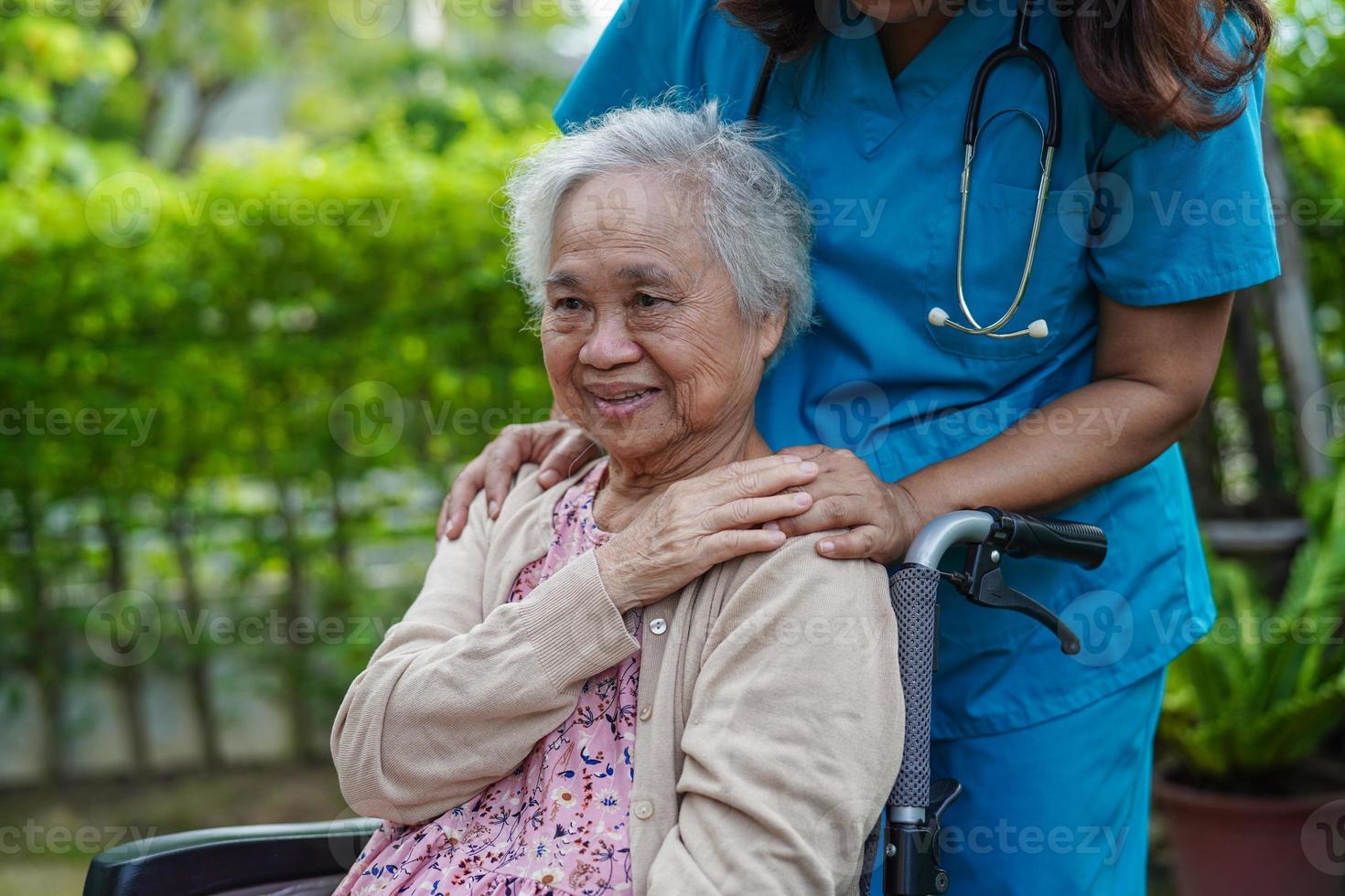 médico ajuda paciente idosa asiática com deficiência sentada na cadeira de rodas no parque, conceito médico. foto