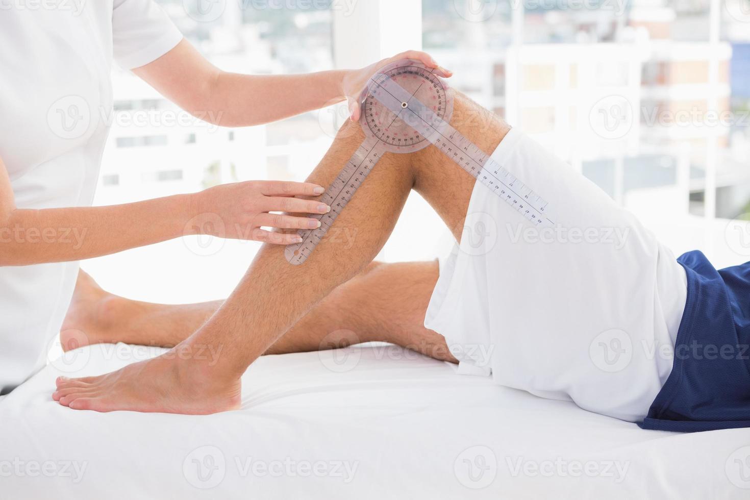 médico examinando a perna do homem foto
