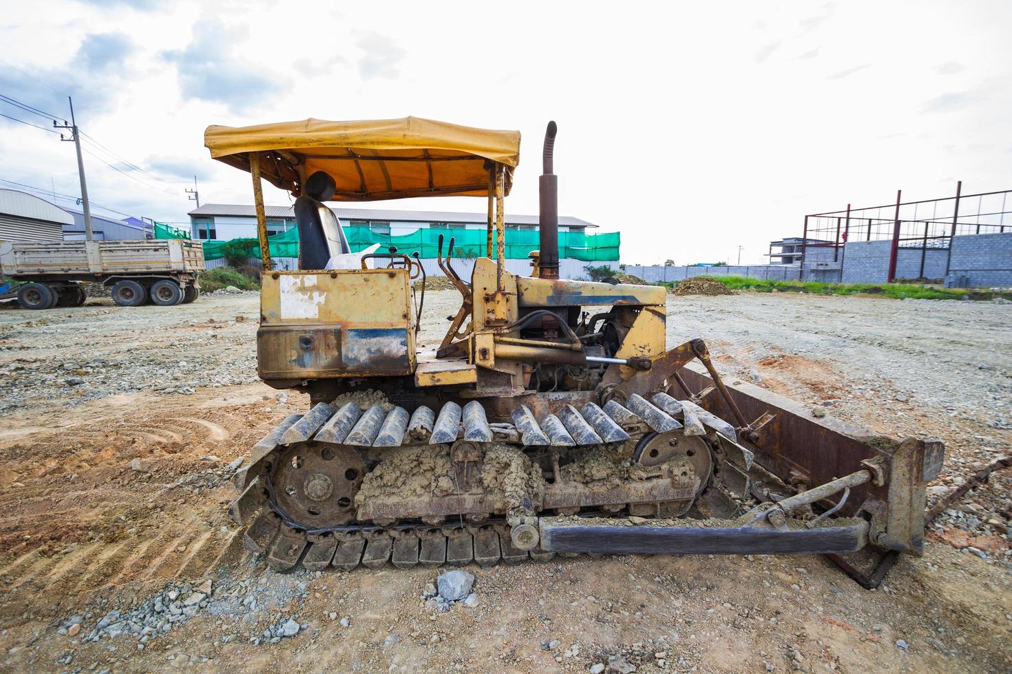 trator de esteira amarelo estacionado em uma clareira em preparação para o solo superficial e um lindo céu azul ao fundo. o conceito de um trator prepara o solo superficial para a construção. foto