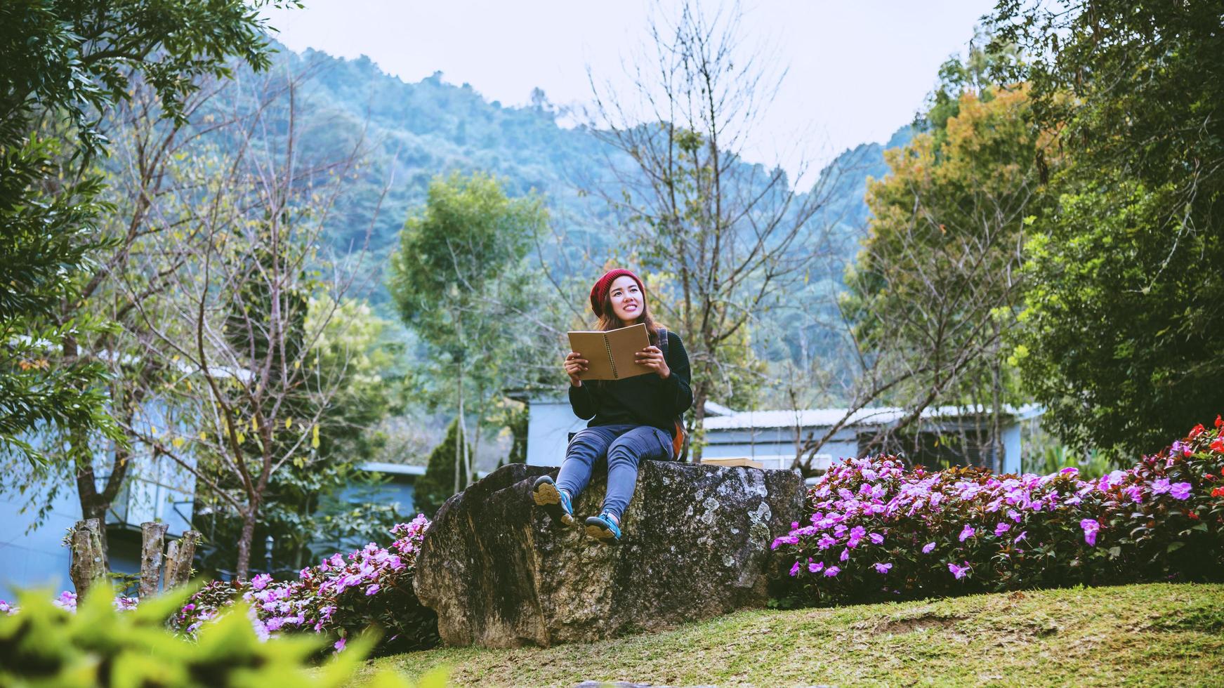 mulher viajar natureza no jardim de flores. relaxe sentado nas pedras e lendo livros em meio à natureza no doi inthanon. foto