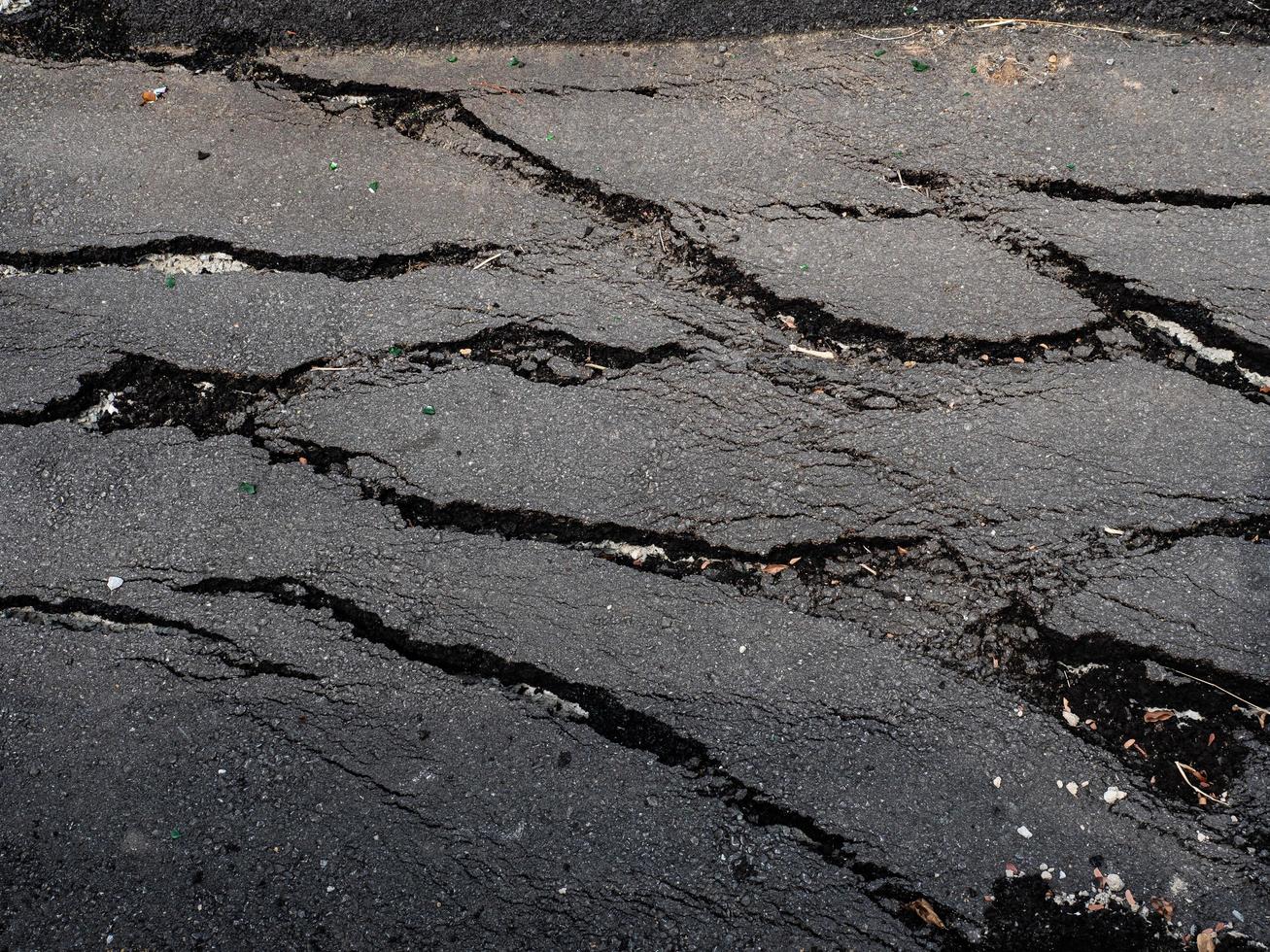 superfície rachada de uma estrada de asfalto foto