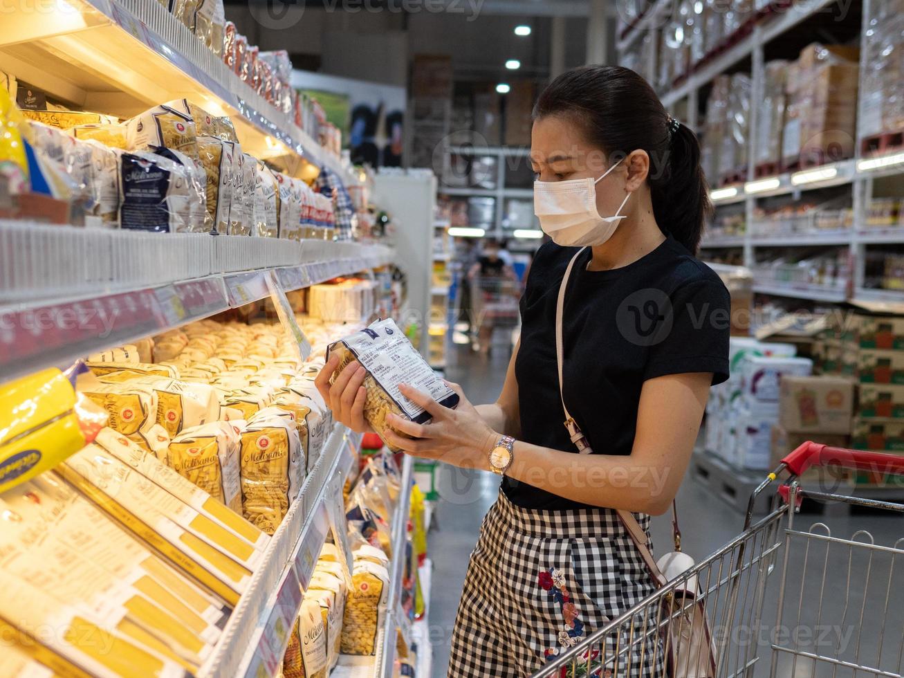 mulher usando máscara protetora descartável fazendo compras no supermercado durante surto de pneumonia por coronavírus foto