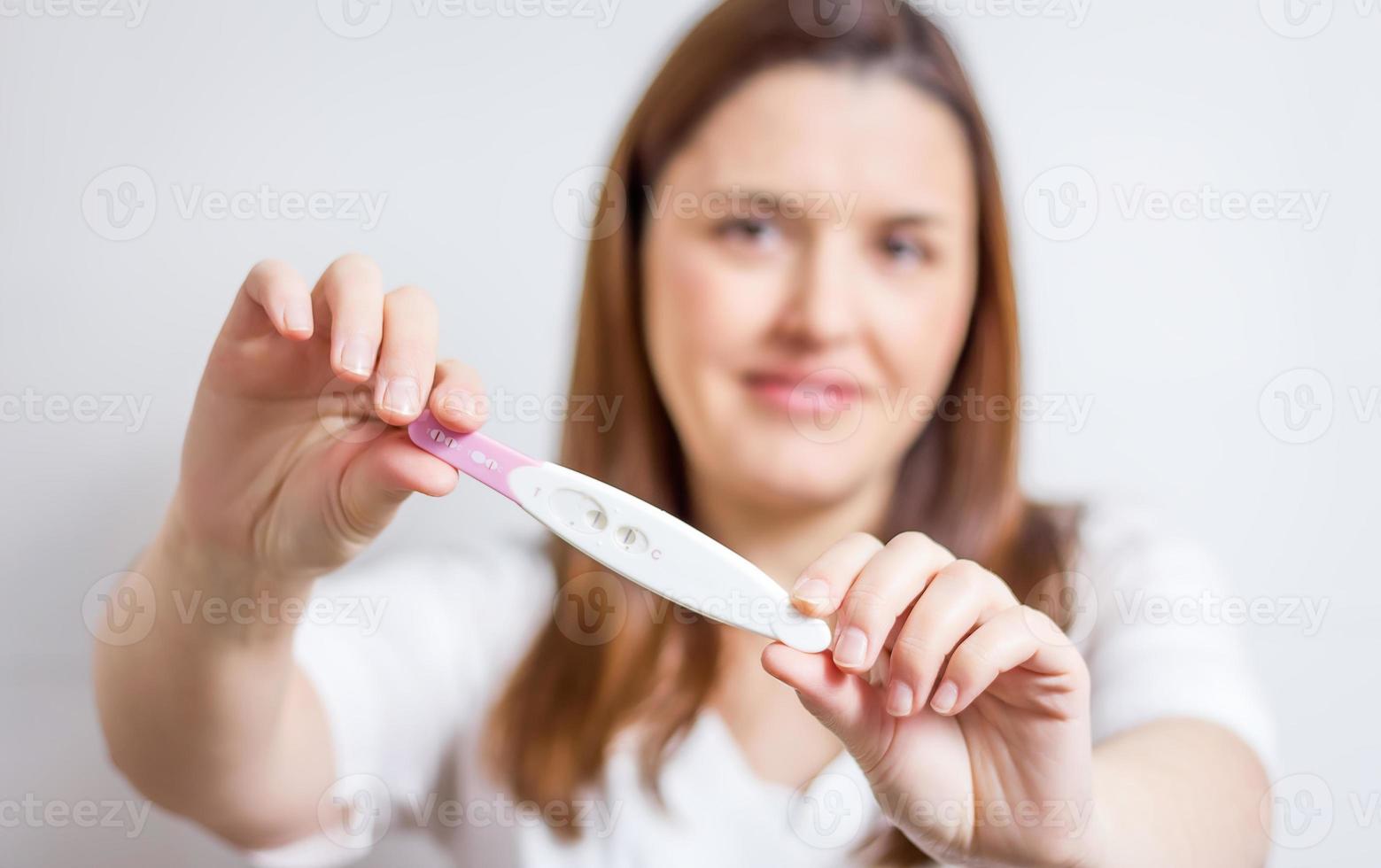 mulher feliz, mostrando seu teste de gravidez positivo foto