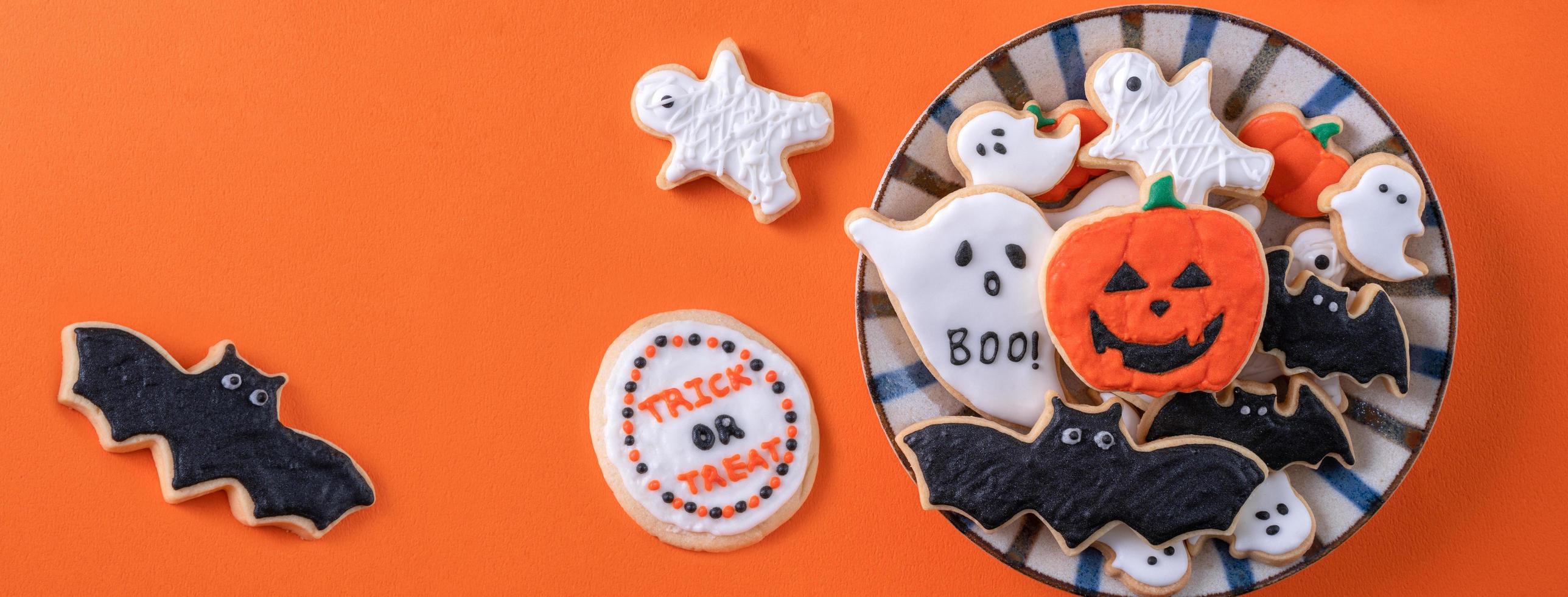 vista superior de biscoitos de açúcar de confeiteiro decorados festivos de halloween em fundo laranja. foto