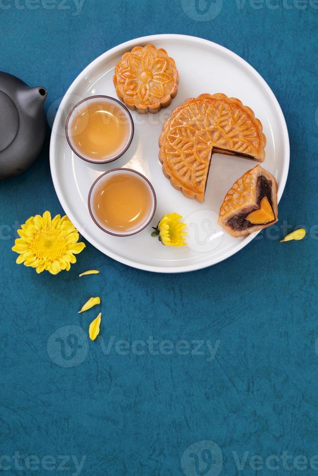 bolo de lua para o festival do meio do outono, delicioso bolo de lua fresco lindo em um prato sobre a mesa de fundo azul, vista superior, conceito de design de layout plano leigo. foto