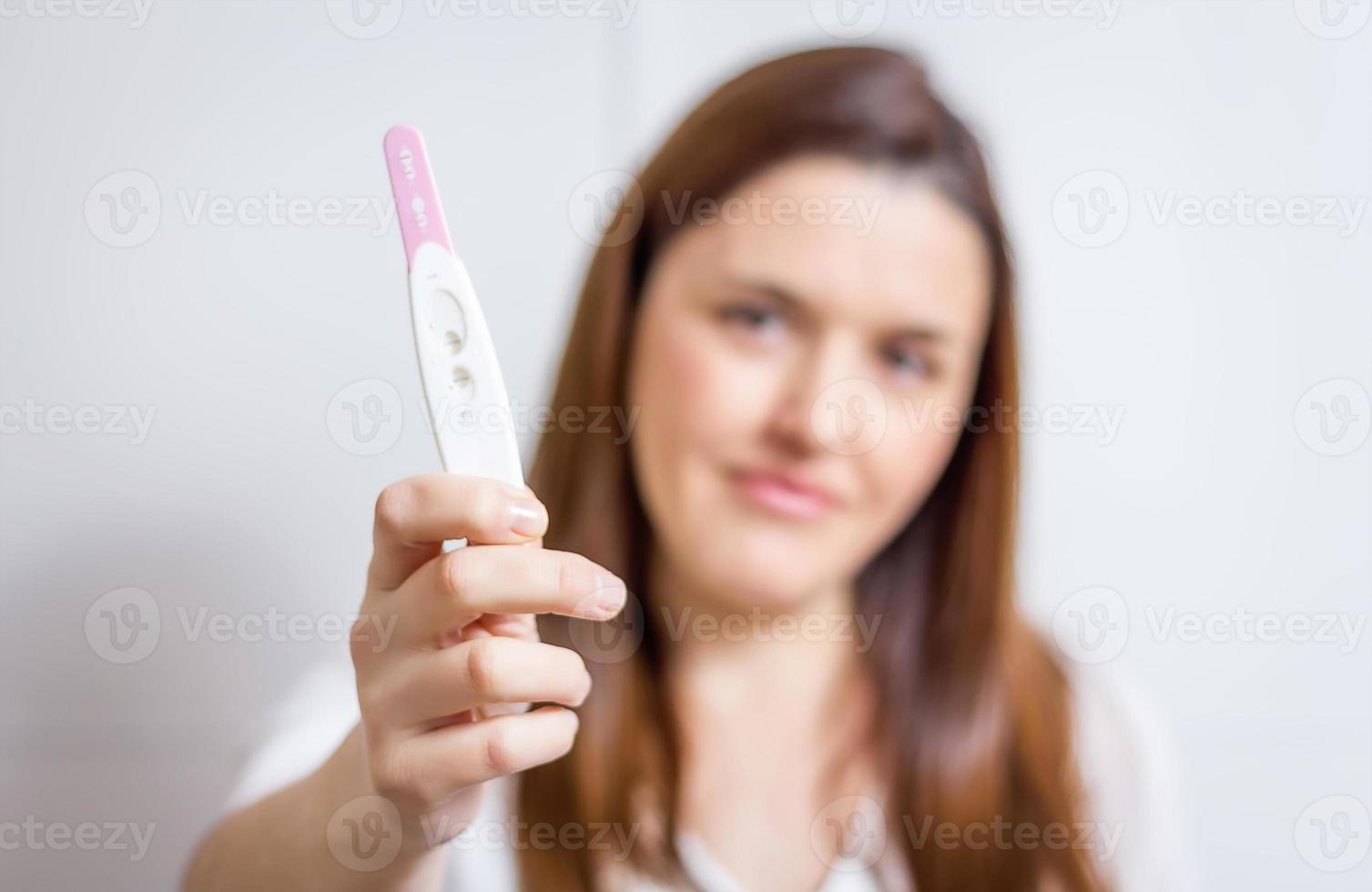 mulher feliz, mostrando seu teste de gravidez positivo foto