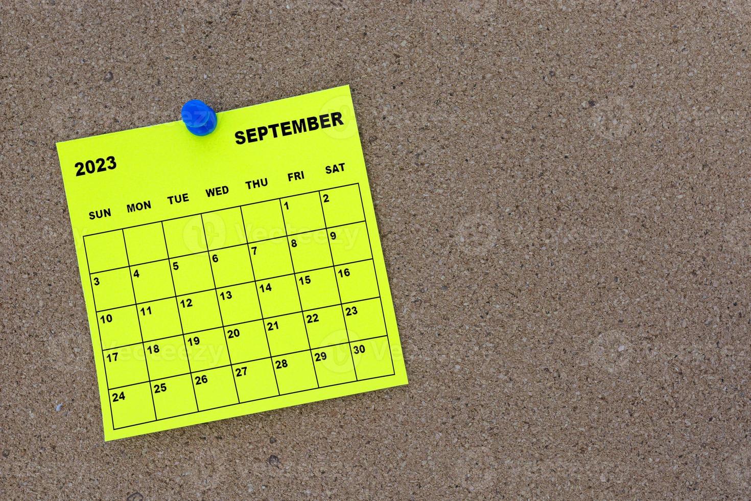 calendário de notas adesivas amarelas de setembro de 2023 com pino no quadro de avisos de cortiça. foto