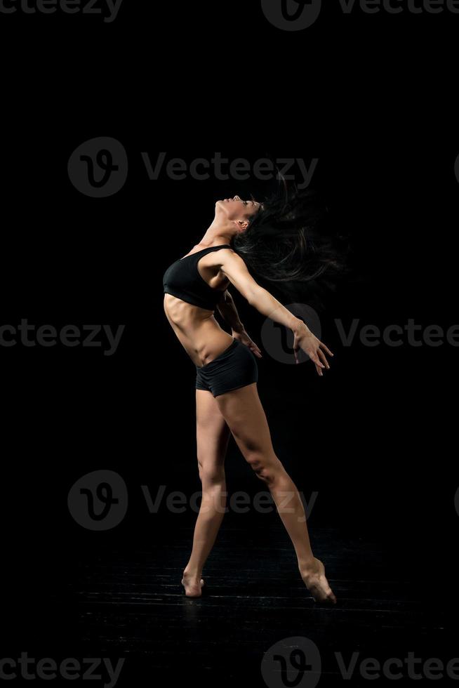 jovem bailarina dançando no fundo preto foto