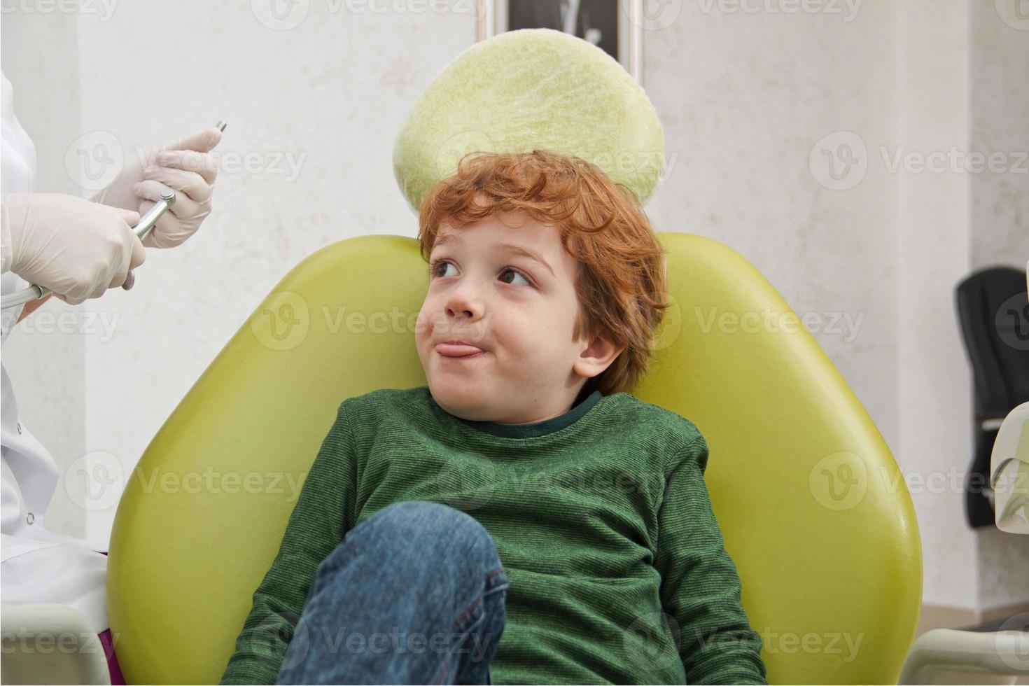 menino bonito, sentado na cadeira no dentista foto