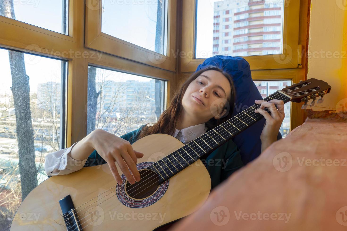 jovem tocando violão clássico na varanda foto