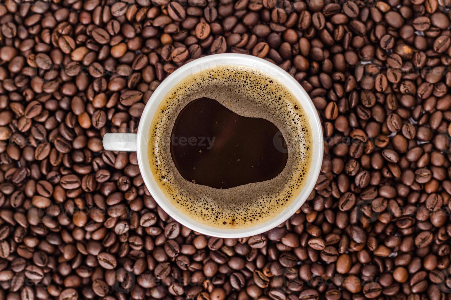 branca xícara de café em uma pilha de grãos de café. foto