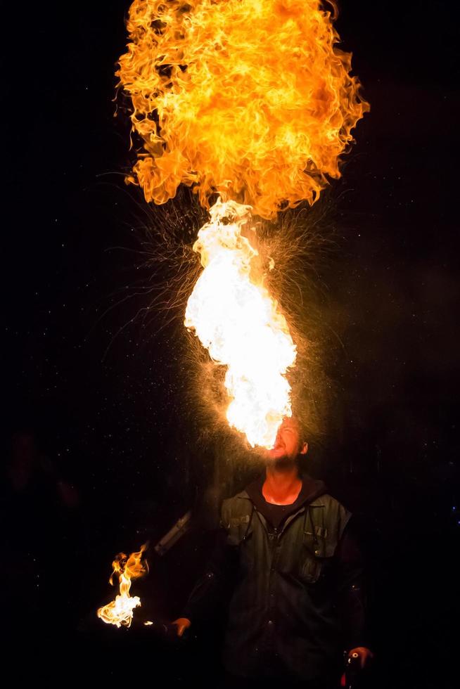 show de fogo no festival ao ar livre. artistas exalar chama, pilar de fogo em um fundo preto - 8 de julho de 2015, rússia, tver. foto