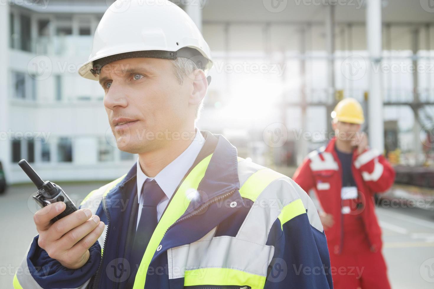 trabalhador masculino usando walkie-talkie com o colega no fundo foto