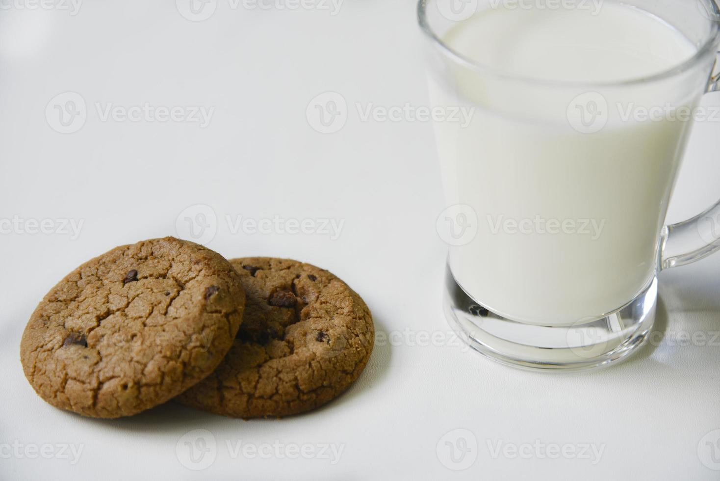 copo de vidro com leite em um fundo branco com biscoitos de aveia. almoço da tarde com biscoitos. biscoitos doces com leite. foto