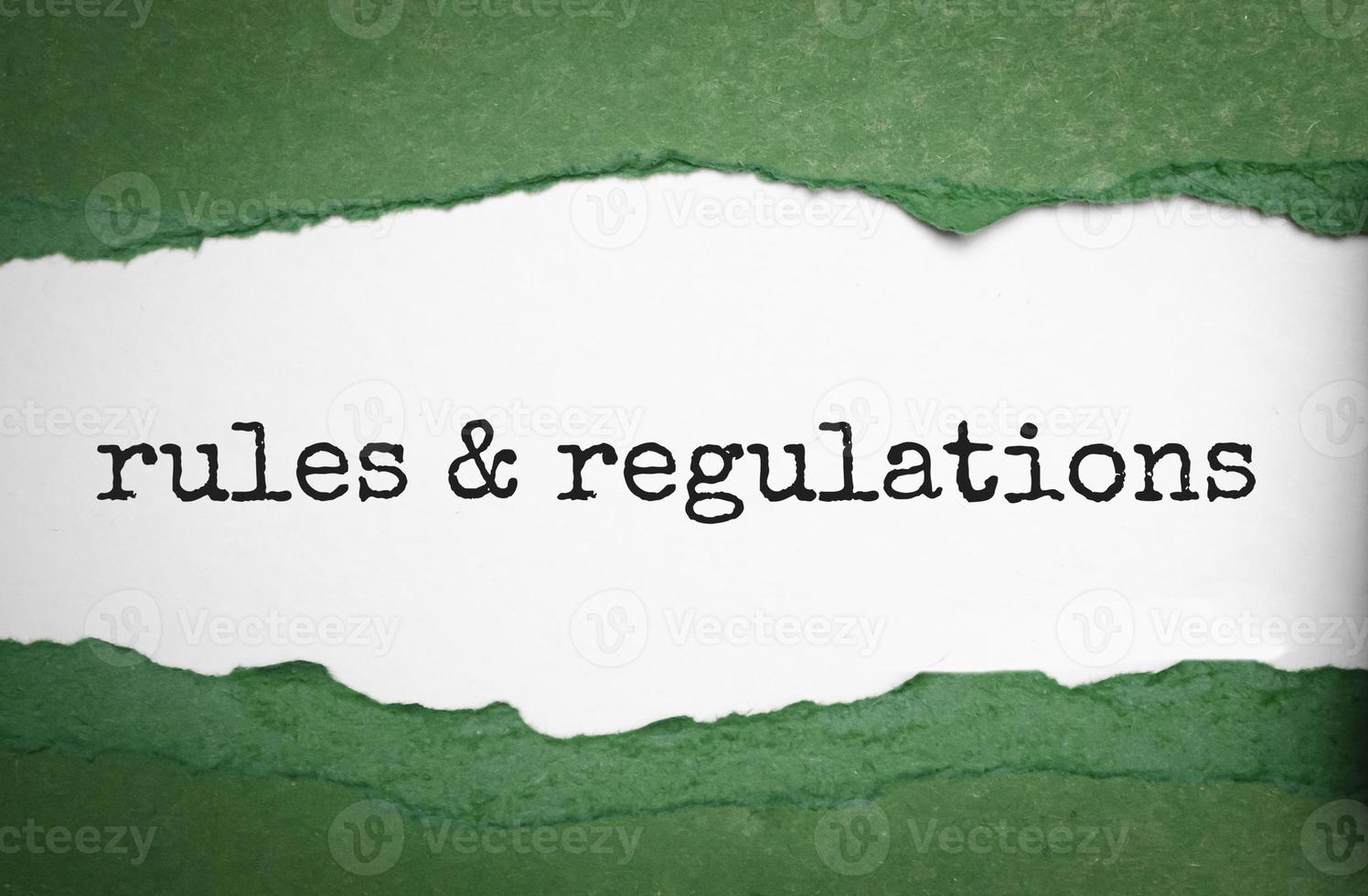 palavra de regras e regulamentos sob papel verde rasgado foto