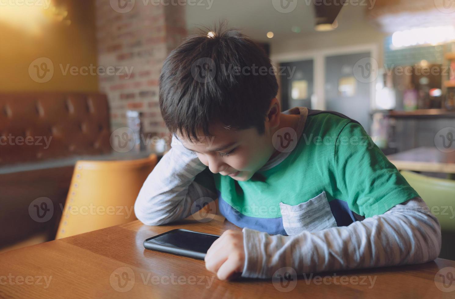 retrato menino jogando no celular enquanto espera por comida