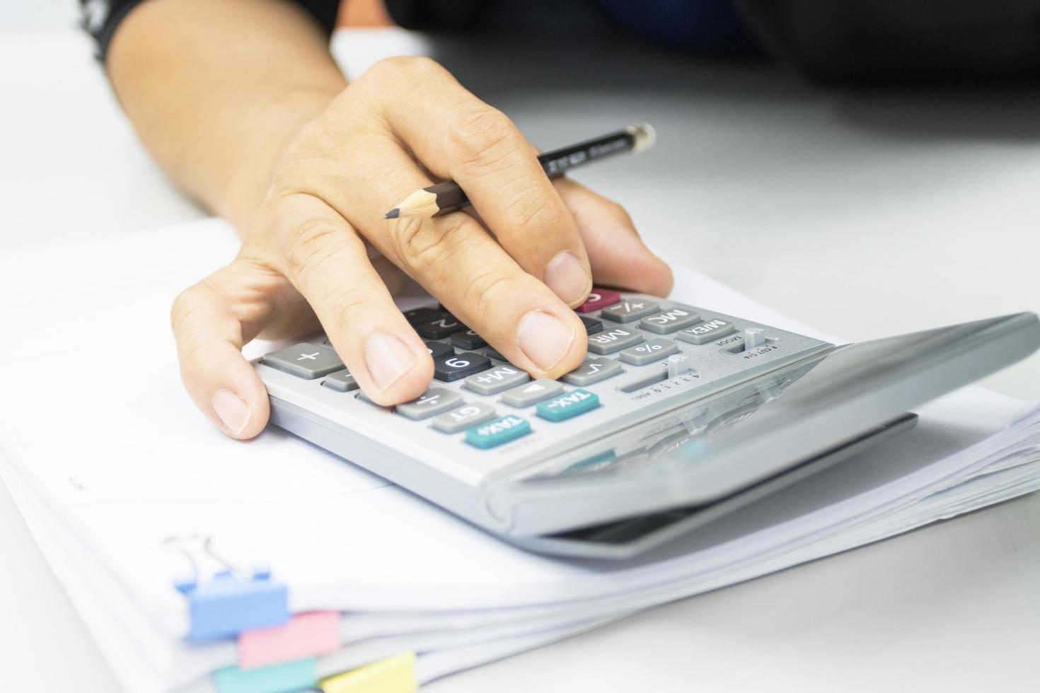 mão do homem usa uma calculadora para calcular receitas e despesas nos conceitos de escritório foto