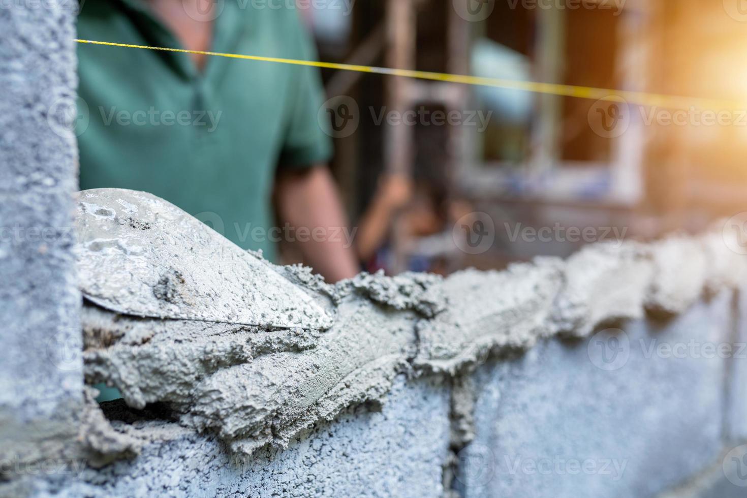 os trabalhadores usam espátulas para construir paredes ou paredes com tijolos e argamassa. foto