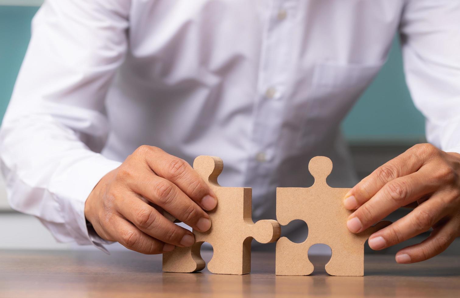 mão de empresário conectando quebra-cabeça na mesa, soluções de negócios. foto