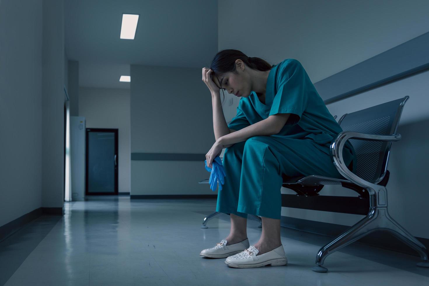 enfermeira médica está sentada no corredor do hospital em frustração e tristeza após falha e conceito de condição corporal do paciente foto