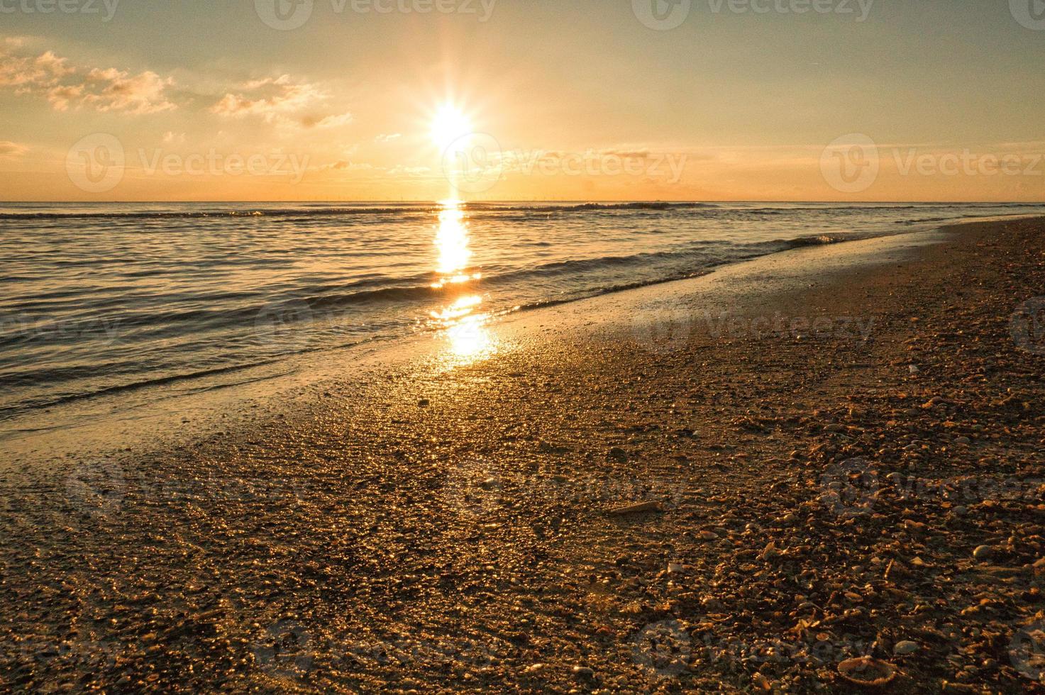 pôr do sol no estande da blavand dinamarca. horas da noite em clima de luz quente foto