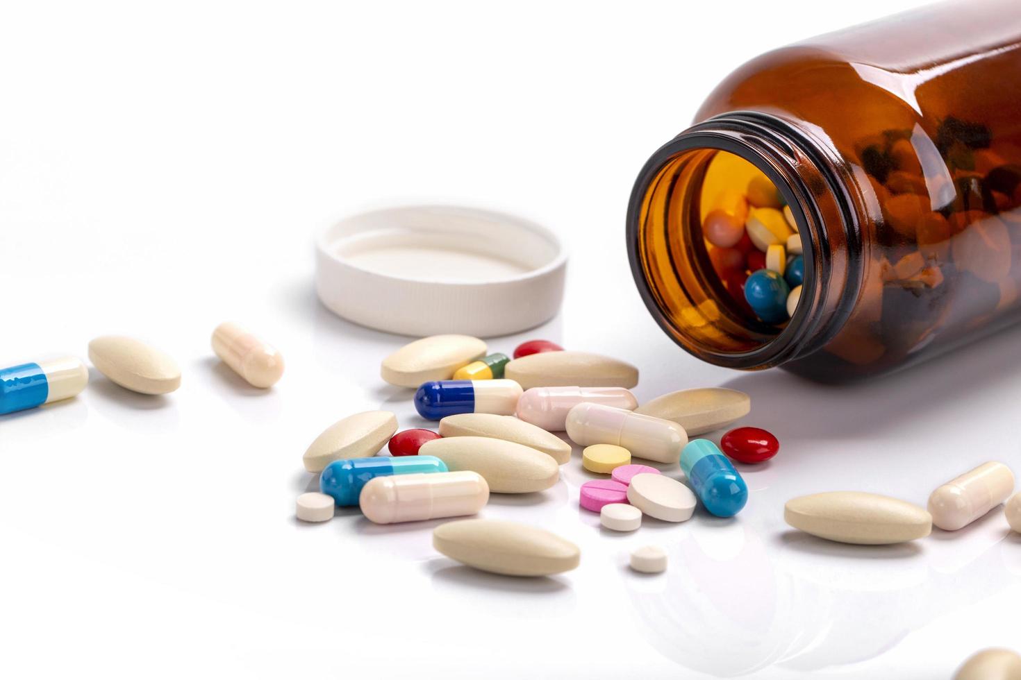 closeup em cápsulas de comprimidos saindo do frasco de comprimidos isolado em um conceito de fundo, saúde e drogas médicas foto
