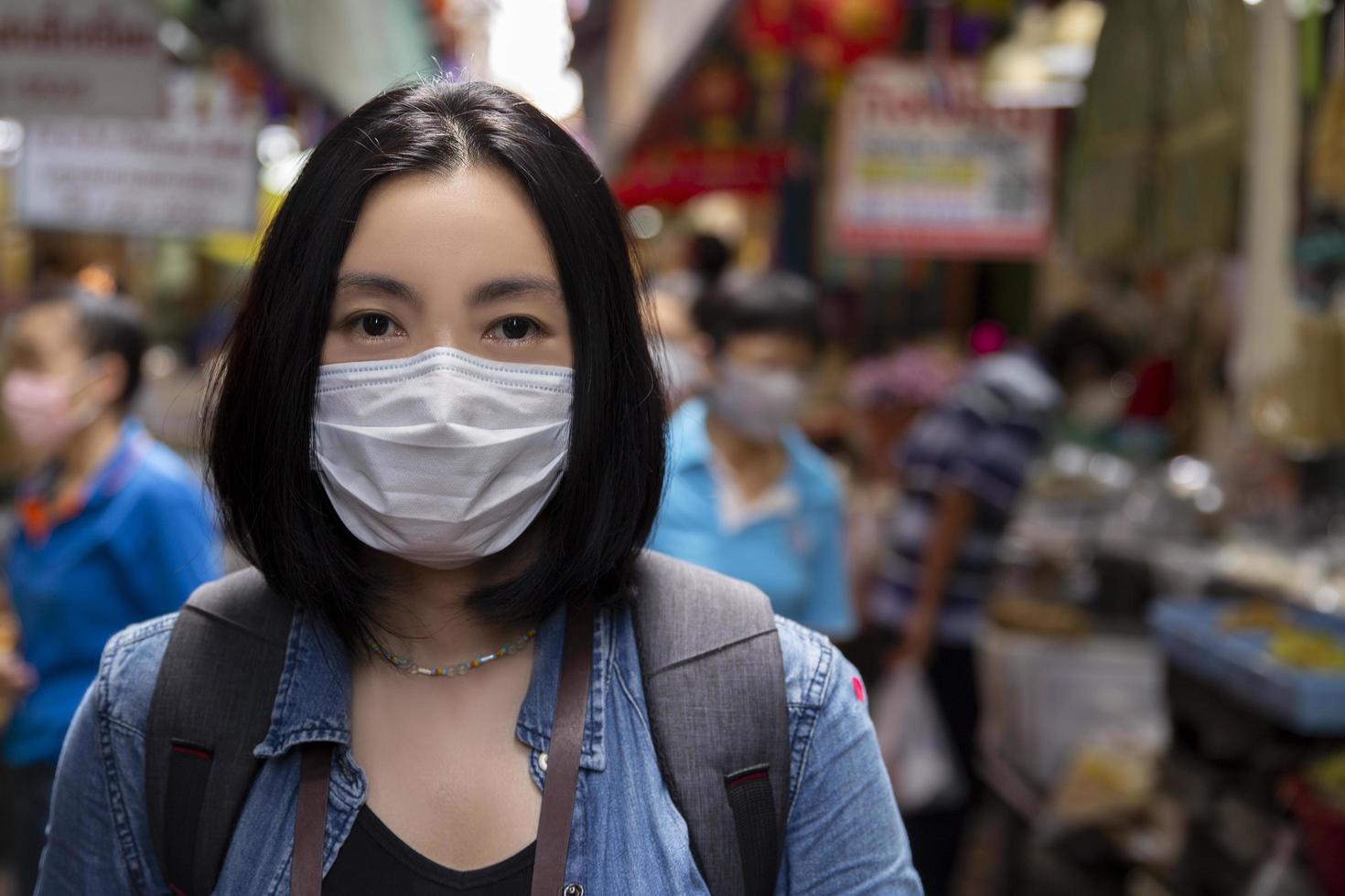 mulher asiática usando máscara cirúrgica protetora para propagação do vírus da doença covid-19 ou prevenção de surtos de coronavírus em área pública foto