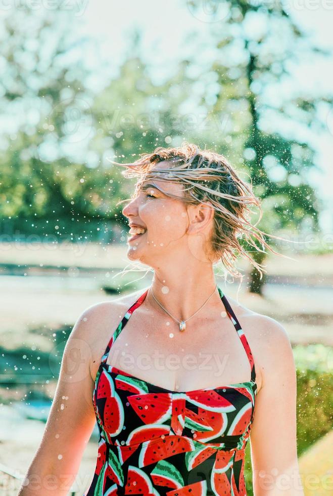 rindo mulher loira emocional com cabelo molhado fazendo salpicos de água. férias, felicidade, diversão, verão, conceito de lazer foto