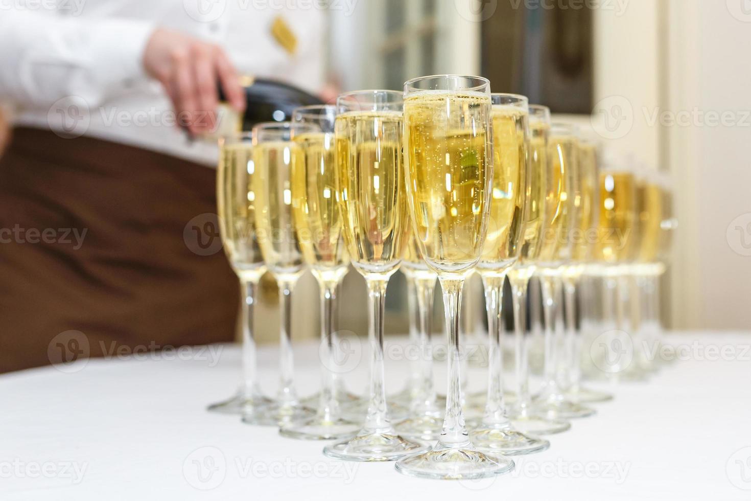 muitos copos turva com champanhe na mesa da festa de recepção na luz de fundo foto