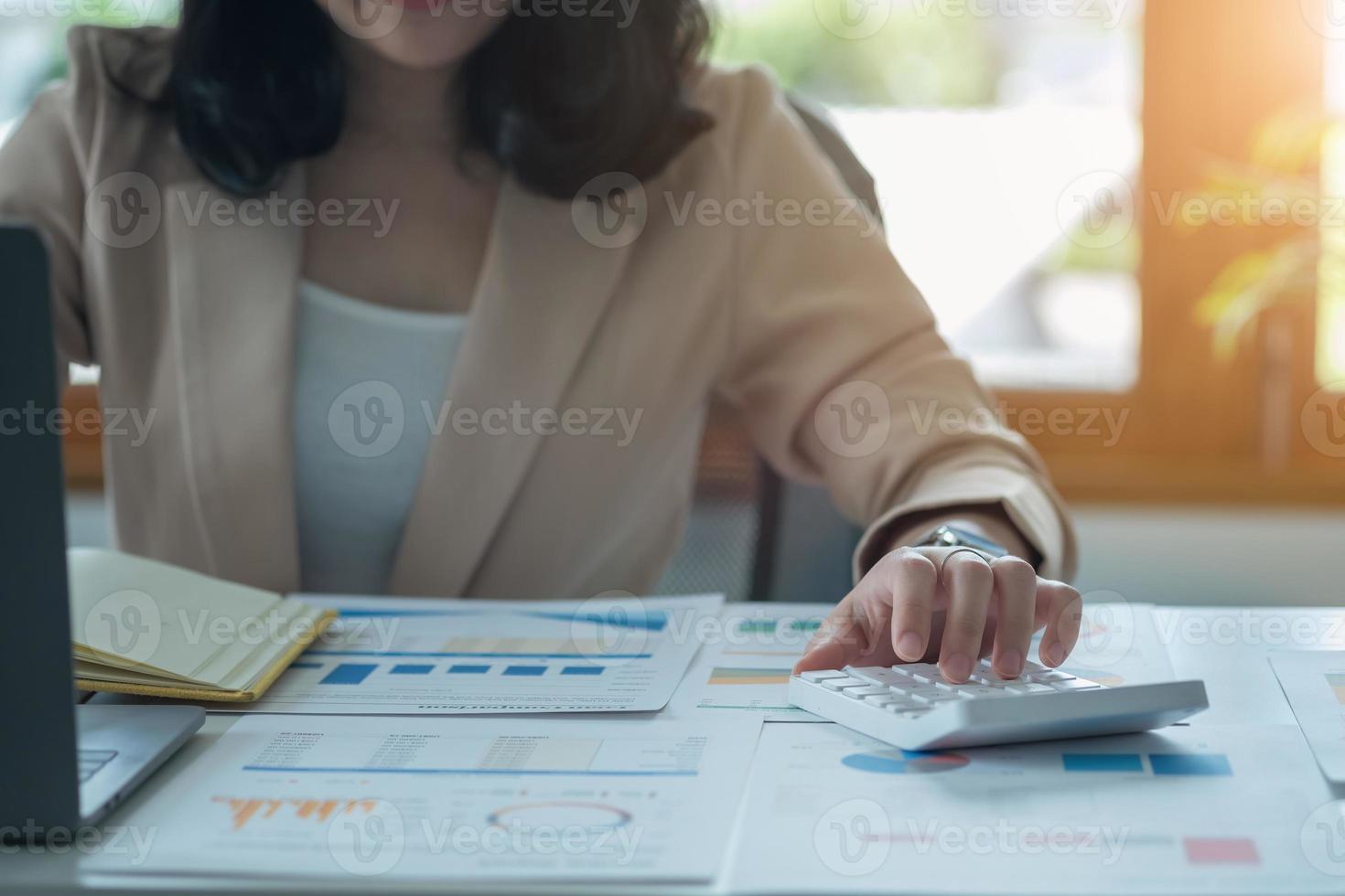 retrato de um contador feminino usando uma calculadora e laptop para calcular o saldo usando gráficos para clientes. foto