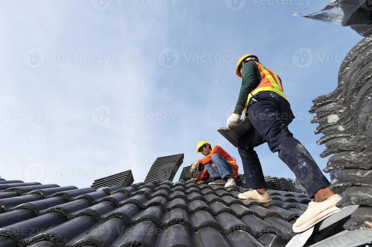 construtores em roupas de trabalho instalam novas ferramentas de cobertura, ferramentas de cobertura, furadeira elétrica e as usam em novos telhados de madeira com chapas de metal foto