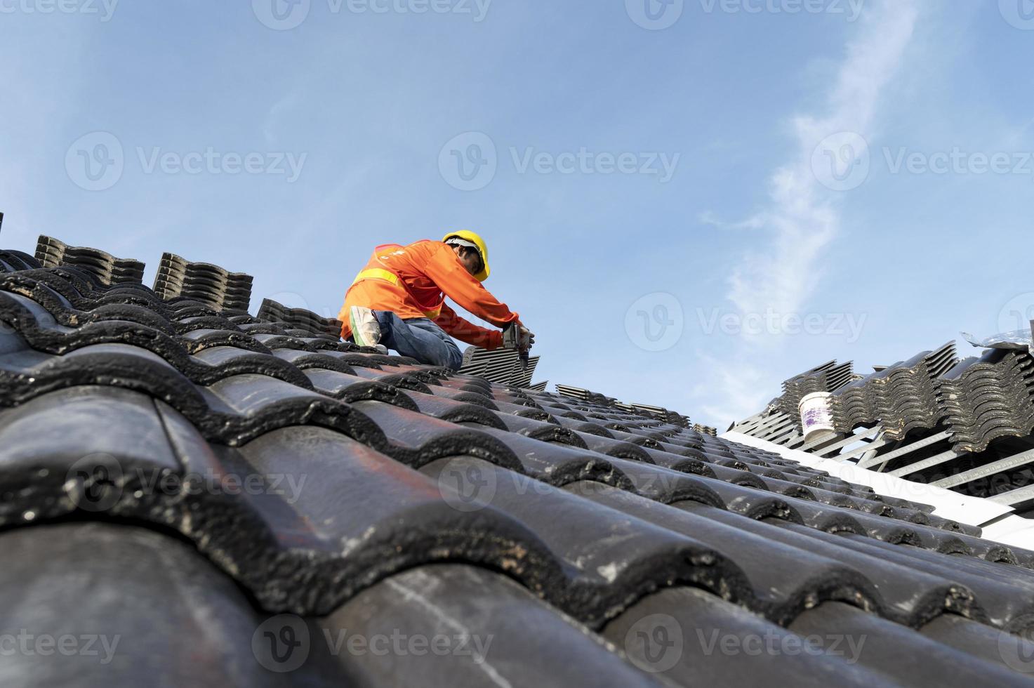 construtores em roupas de trabalho instalam novas ferramentas de cobertura, ferramentas de cobertura, furadeira elétrica e as usam em novos telhados de madeira com chapas de metal foto