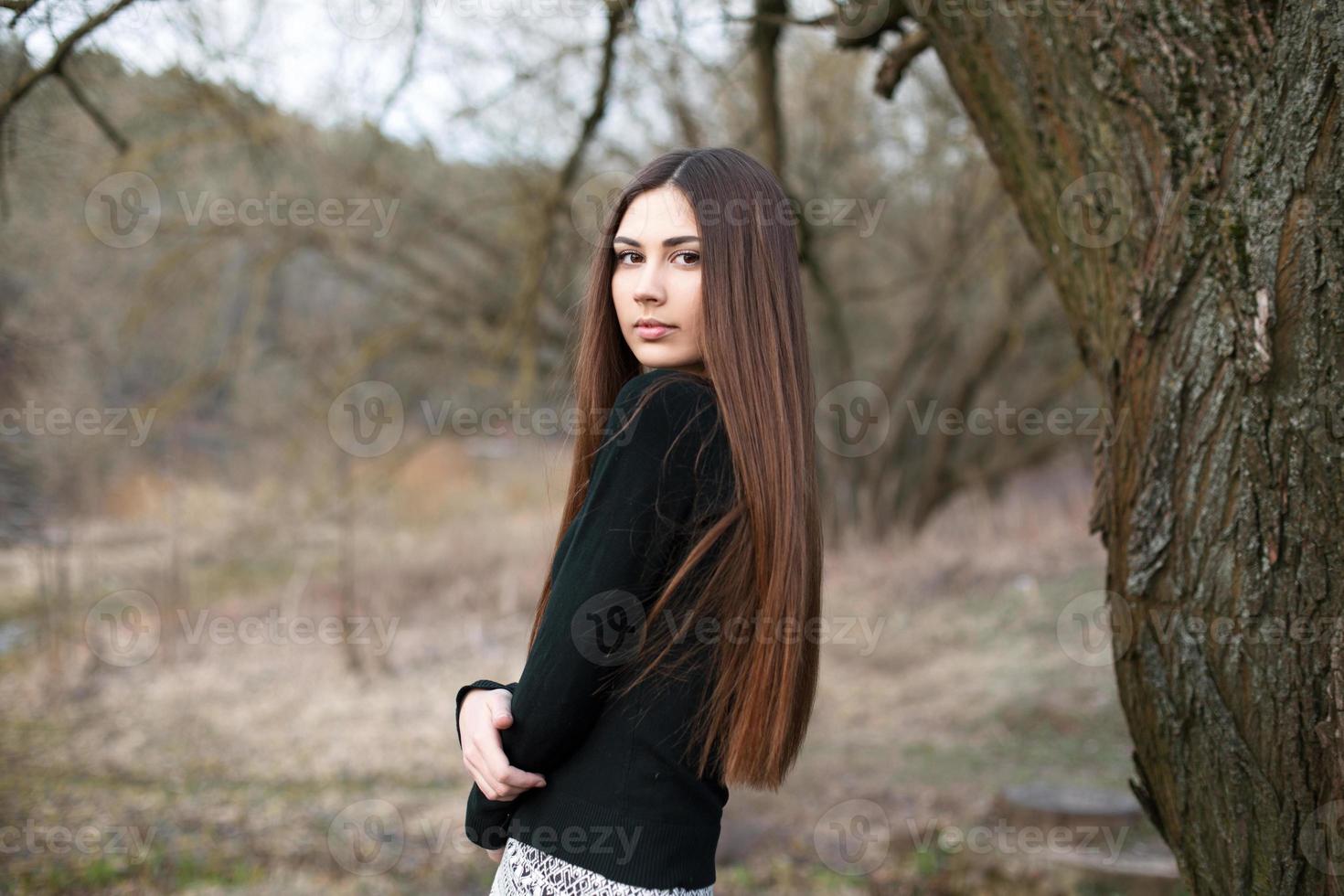 linda jovem de pé perto de uma árvore no fundo do jardim. foto