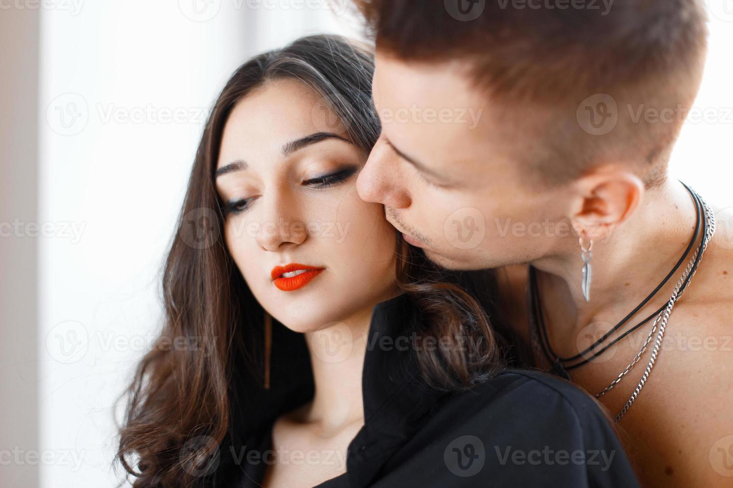 jovem casal lindo. homem beijando sua namorada na bochecha foto