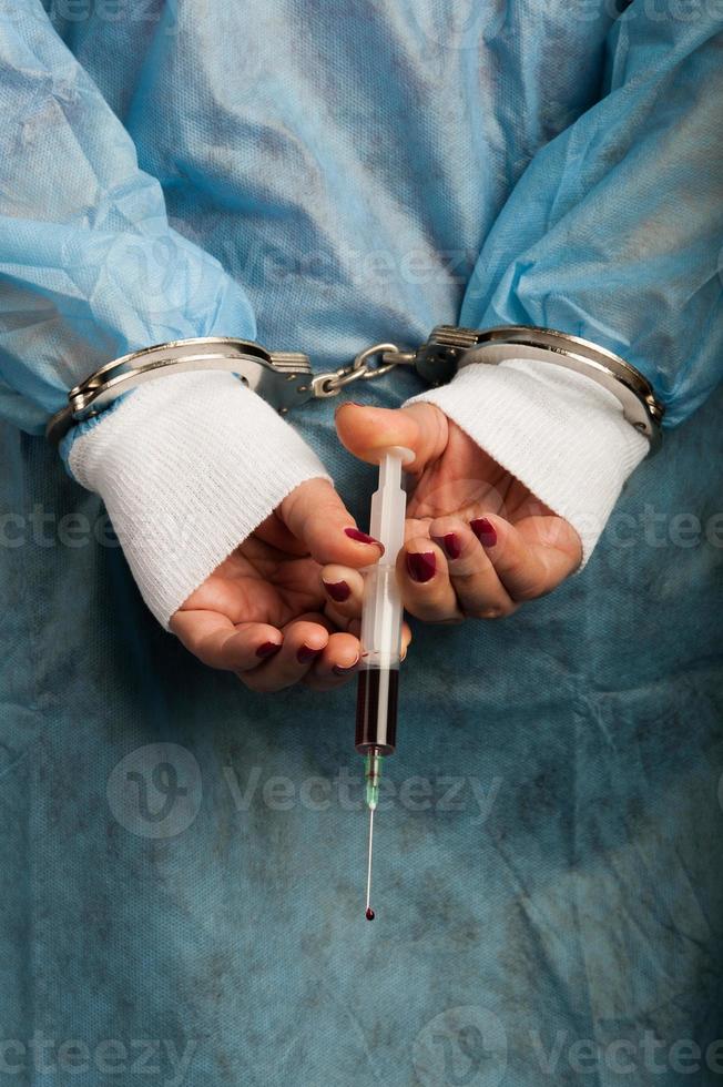 pessoa médica algemada criminosa com injetor sangrento na mão foto