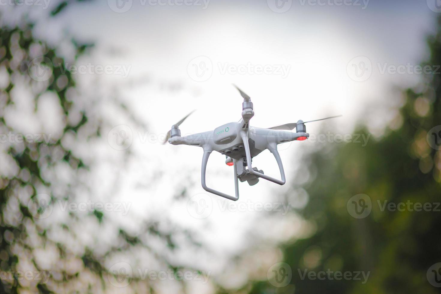 quadrocopter voador branco com câmera no fundo da floresta verde foto