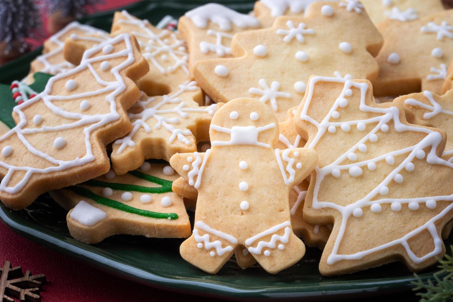 close-up de biscoitos de açúcar de natal em um prato no fundo da mesa vermelha. foto