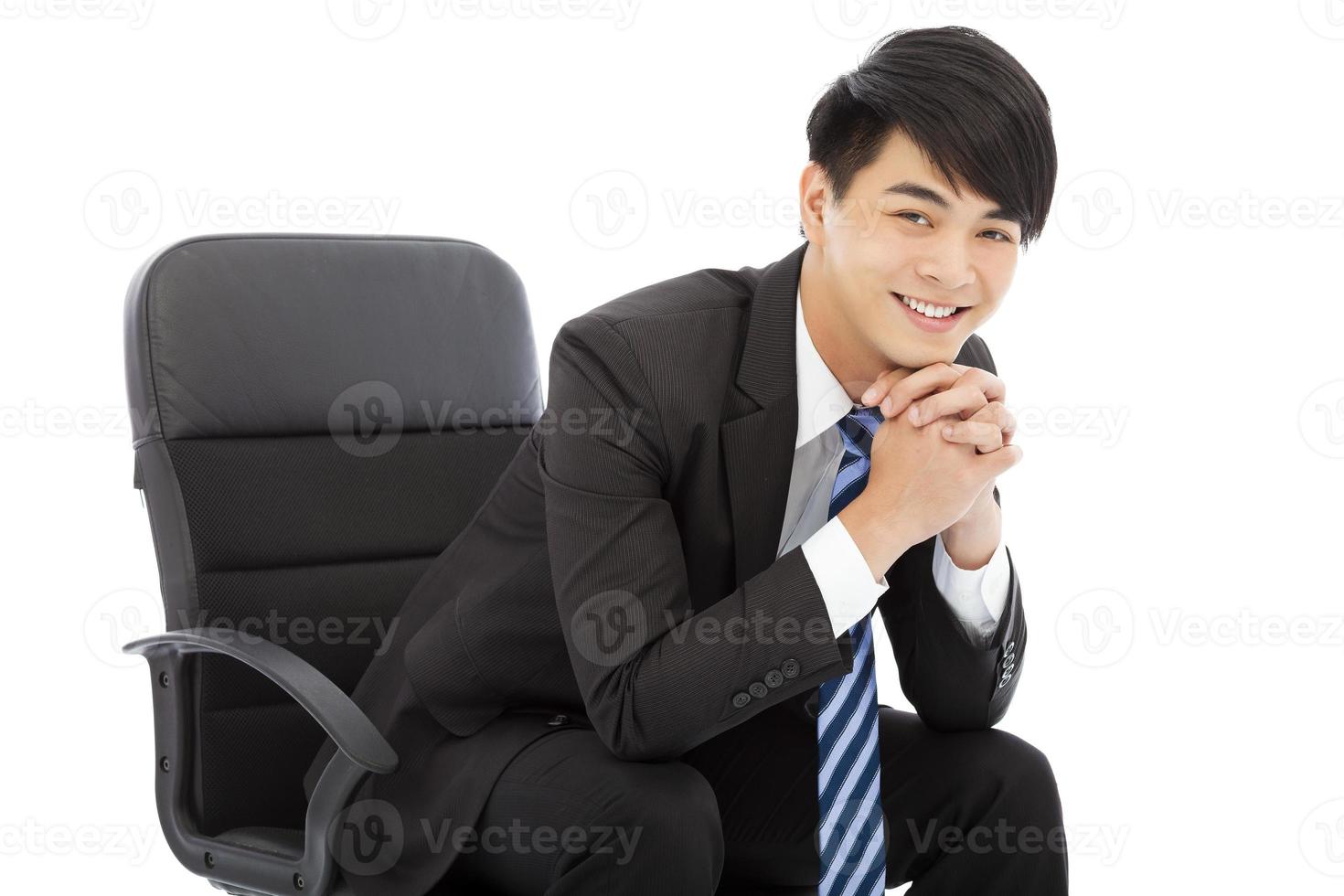 sorridente jovem empresário sentado em uma cadeira foto