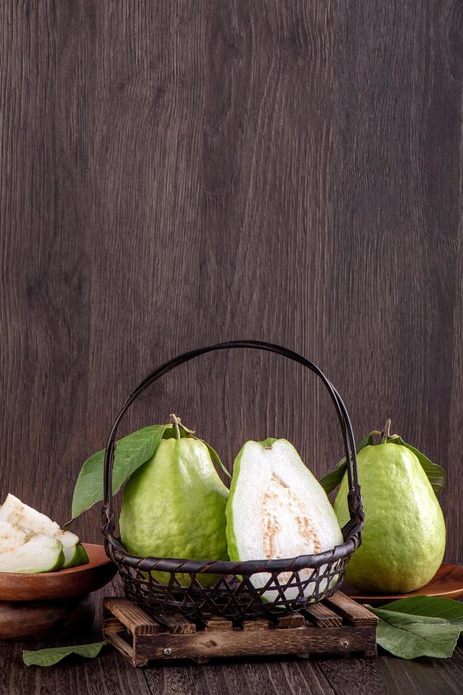 close-up de deliciosa goiaba com folhas verdes frescas em fundo de madeira. foto