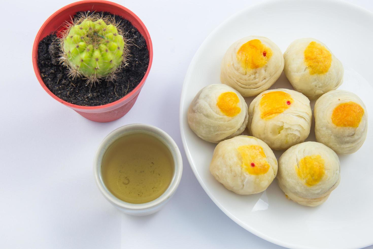 feijão de mung de massa chinesa ou bolo de lua com gema de ovo no prato e xícara de chá verde e pote de cacto foto