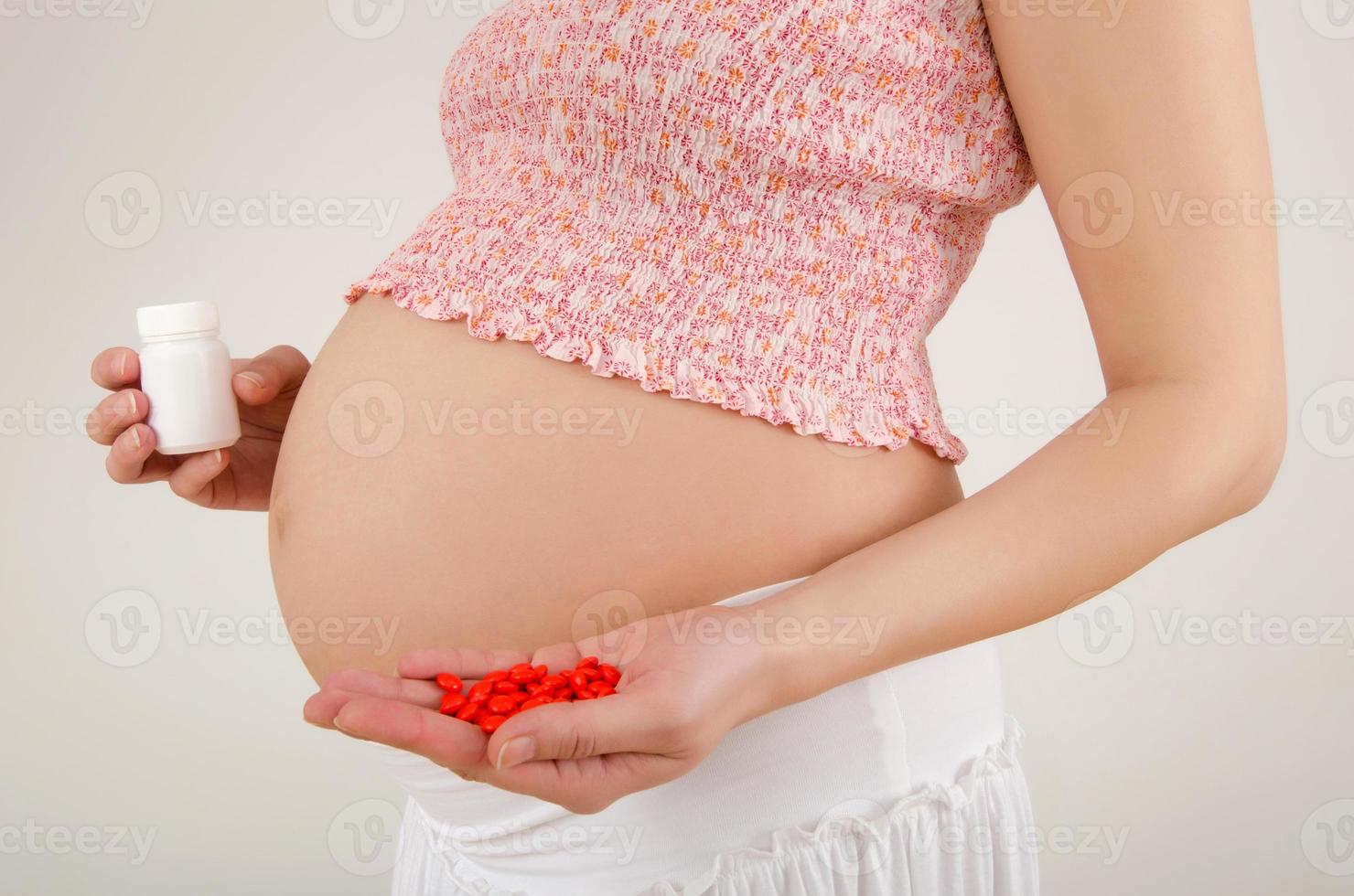 mulher esperando um bebê segurando comprimidos nas mãos dela. foto