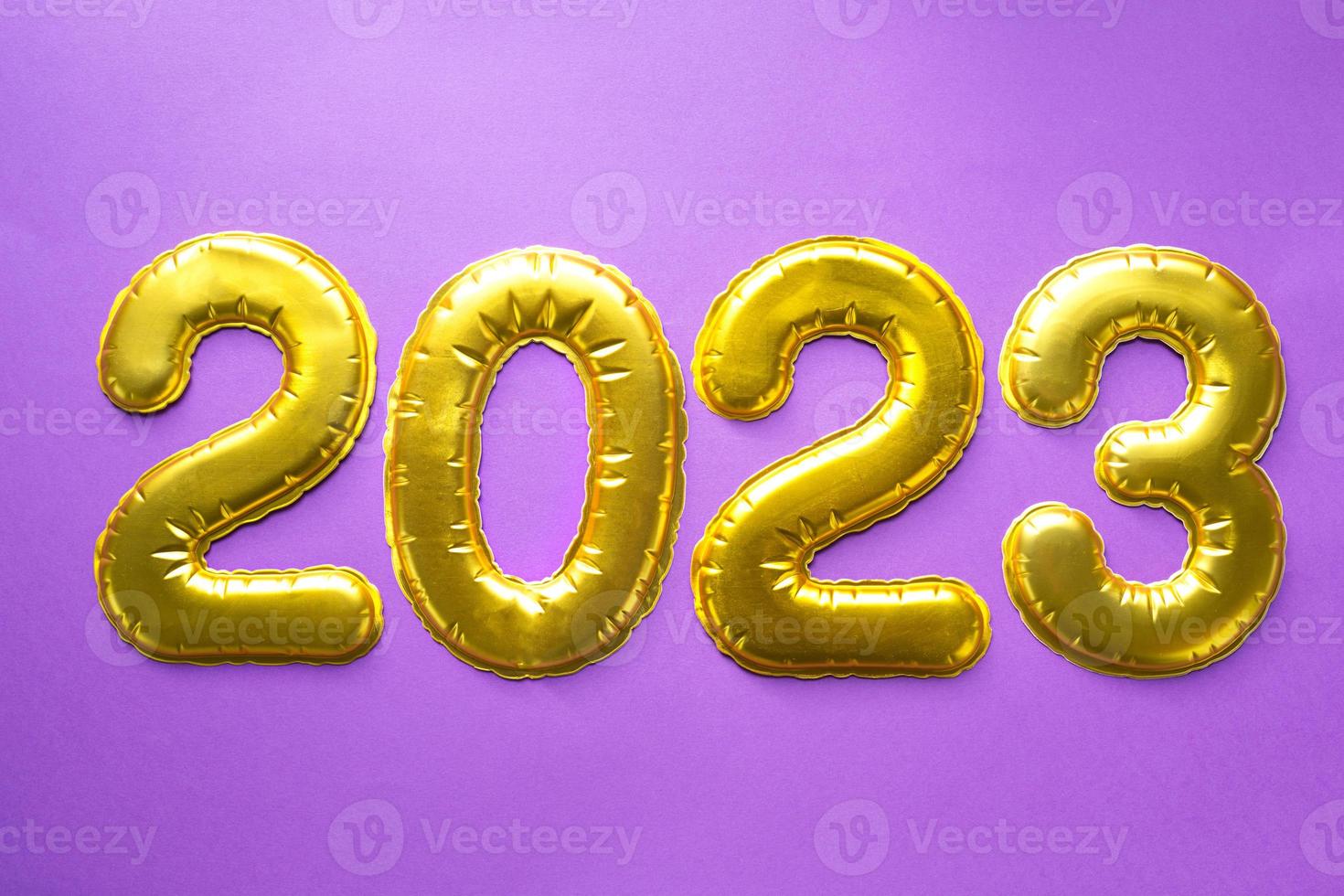 feliz ano novo - números dourados 2023 em um fundo roxo com lantejoulas, estrelas, glitter, luzes de guirlandas. saudações, cartão postal. calendário, capa. foto