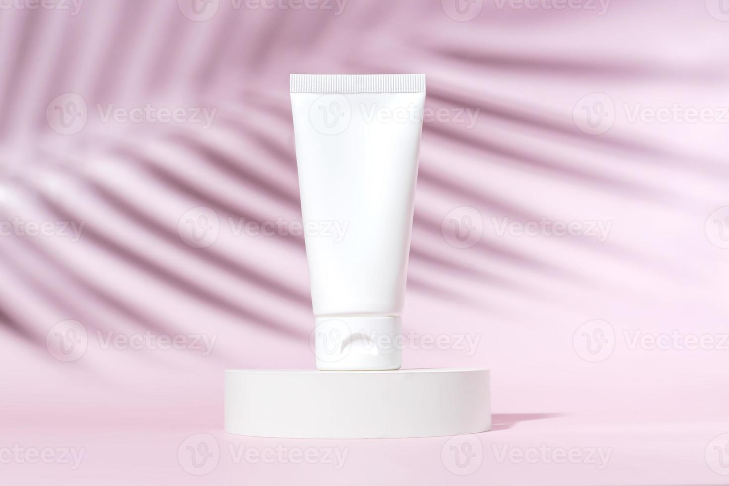 creme para o rosto ou para as mãos em um tubo de plástico branco em um fundo rosa com sombra de uma palmeira tropical. acessório cosmético feminino para maquiagem. maquete, identidade, copie o espaço foto