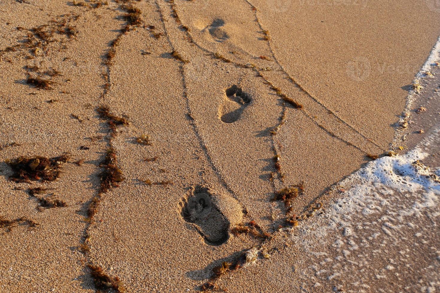 pegadas na areia na praia da cidade. foto