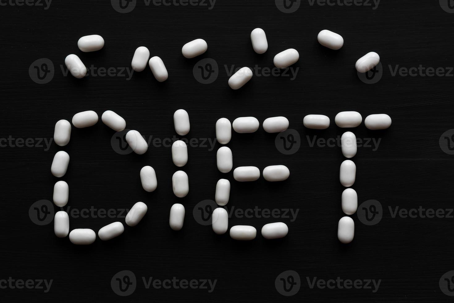 conceito médico escrito com pílulas palavra dieta em fundo preto de madeira com espaço de cópia foto