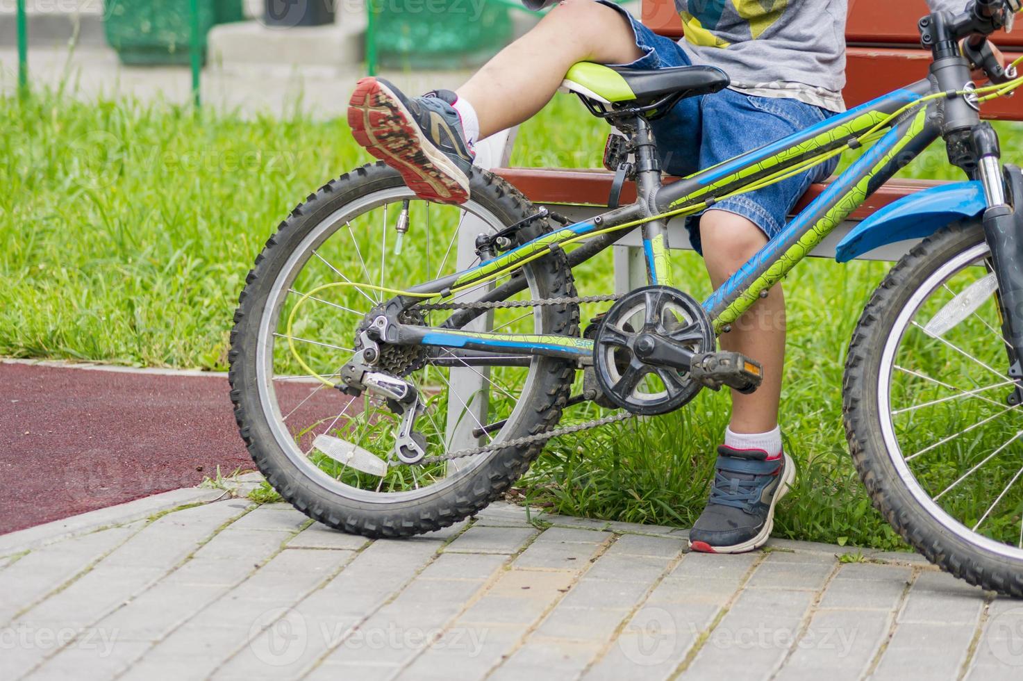 menino adolescente descansando no banco com bicicleta foto