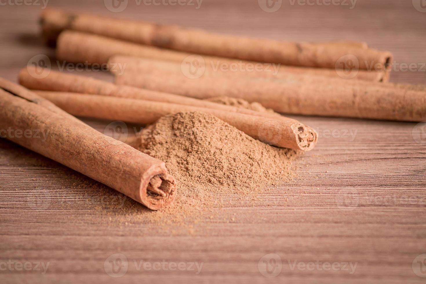 paus de canela e pó na mesa de madeira. foto