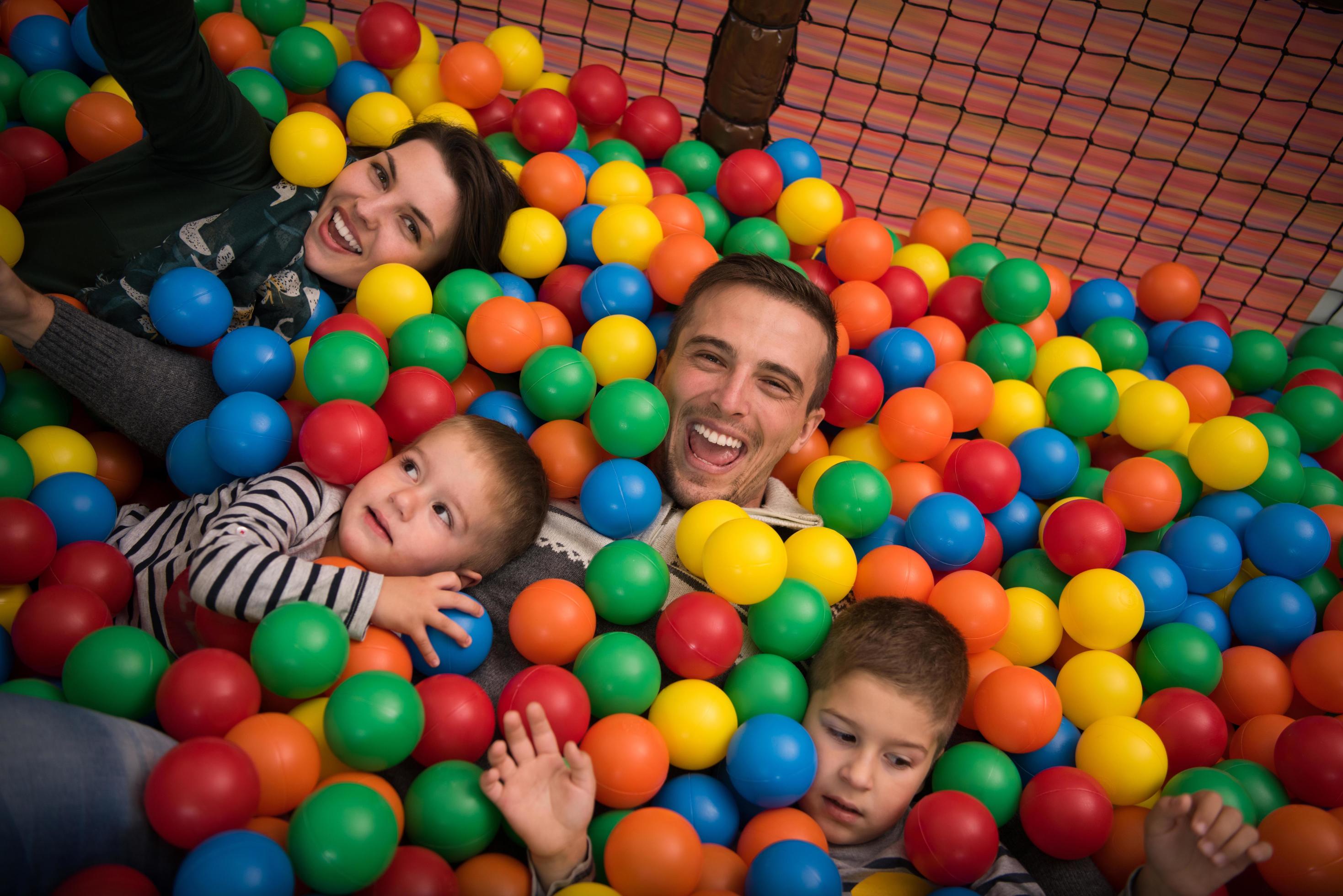 pais jovens com filhos em uma sala de jogos infantil Foto Grátis