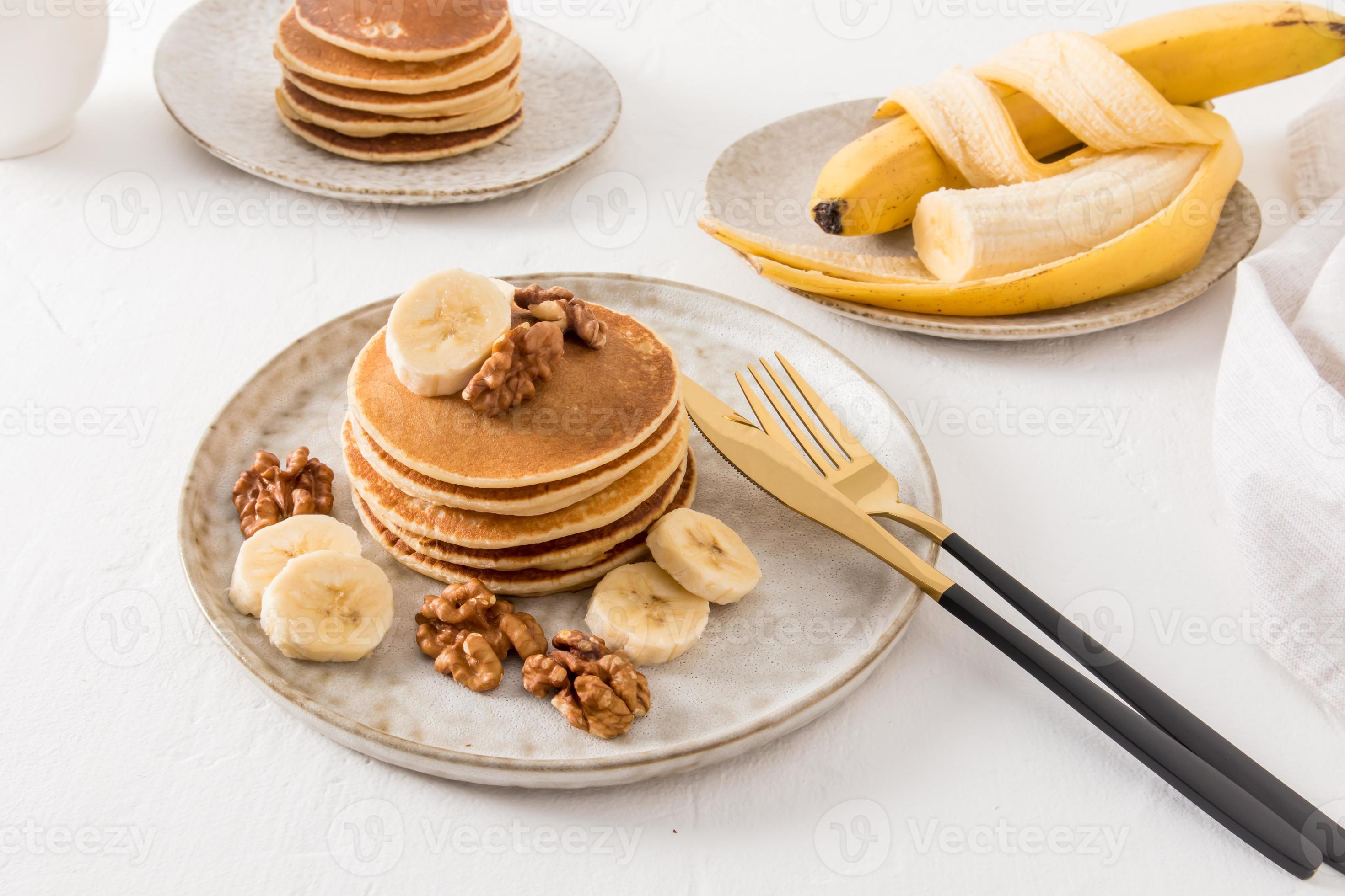 Pilha de panquecas caseiras em frigideira de ferro com mirtilos, banana e  folhas de hortelã em madeira rústica.